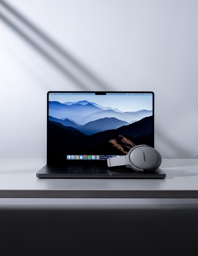 En Macbook pro på et hvidt bord, med et gråt Bose headset